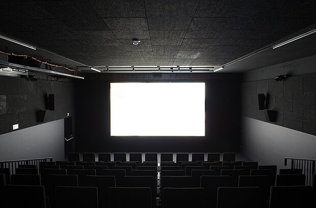 
            
                Ein schwarzer abgedunkelter Raum mit einer weißen Leinwand.
            
        