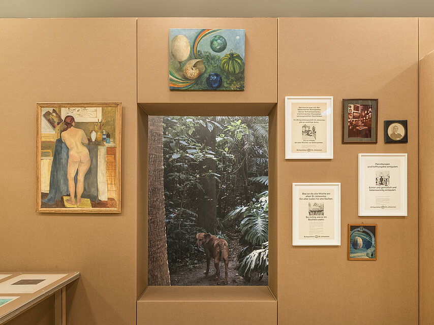 Cardboard wall in brown, in the centre a kind of window with a tree, various works of art around the window