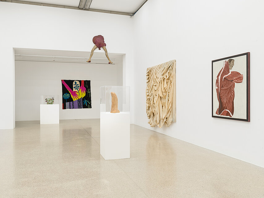 Ausstellungsraum mit verschiedenen bunten Kunstwerken an den Wänden und auf Sockeln