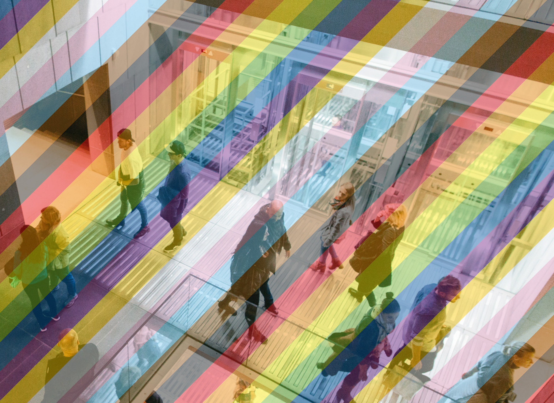 Blick ins Treppenhaus des mumok mit verglasten Fahrstühlen, es gehen mehrere Menschen auf unterschiedlichen Ebenen herum. Das Bild ist mit einem transparenten Regenbogen versehen.