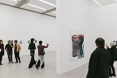 Visitors in the Tobias Pils. Shh exhibition at mumok, standing in front of color-reduced paintings.