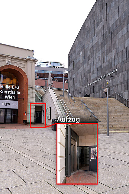 Außenbereich mit Treppenanlage zwischen Gebäuden, hervorgehoben ist der Zugang zu einem Aufzug in einem seitlichen Durchgang. / Outdoor area with a staircase between buildings, highlighting access to an elevator located in a side passage.