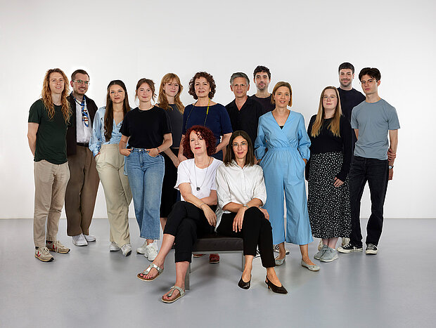 
            
                eine Gruppe von Personen vor einer weißen Wand, vier davon sitzen im Vordergrund auf einer Bank: Das Team Marketing und Kommunikation im mumok
            
        