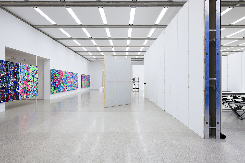  White exhibition walls. On the left, large pictures with neon-coloured patterns.