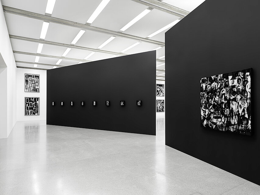 black walls set up in the centre of the exhibition space, with abstract, black and white works of art by Adam Pendleton hanging on the walls