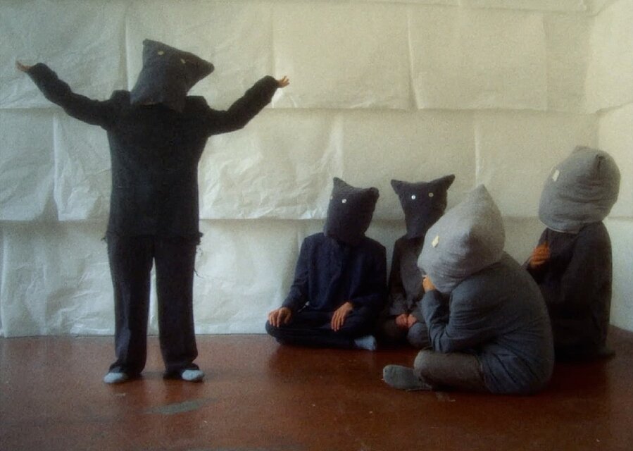 Film Still: Gernot Wieland, Bird in Italien is Uccello. Menschen mit Masken auf dem Kopf / People with masks on their heads