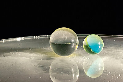 two almost transparent spheres rest on a transparent surface: detail of a work by Liliane Lijn