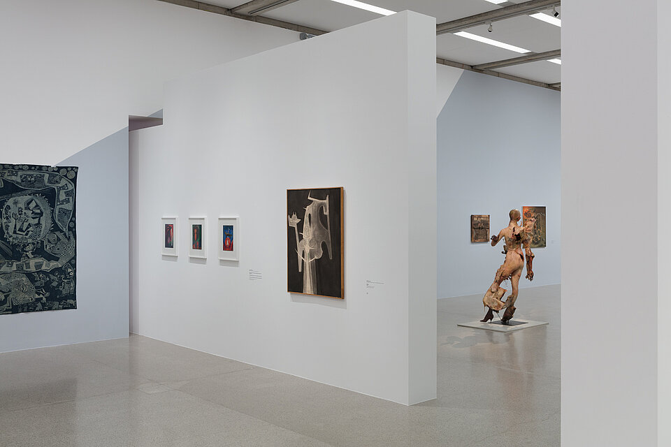 Two large-format pictures on the left and in the centre. In between, three further small-format pictures. A figurative sculpture in front of further pictures in the background.