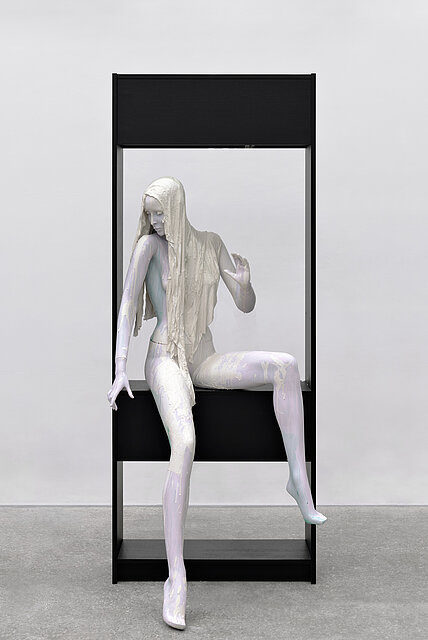 A colourful mannequin sits in a black frame.