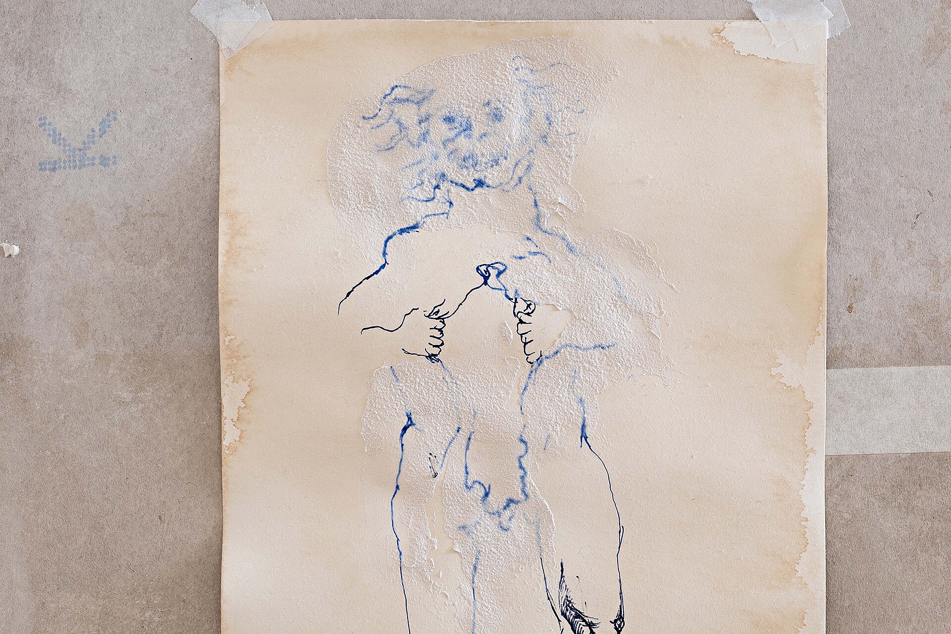 Aufgeklebtes Blatt mit verblasster blauer Linienzeichnung einer stehenden menschlichen Figur auf strukturierter, teils fleckiger Wandfläche. / Taped sheet showing a faded blue line drawing of a standing human figure on a textured, partially stained wall surface.