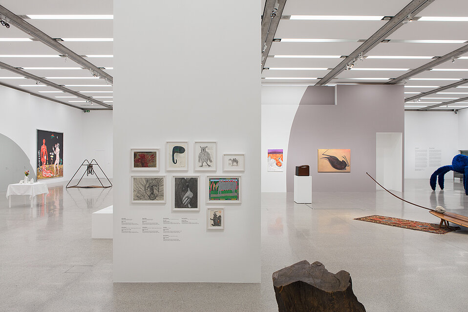 Eight small-format drawings in the centre of the wall. In front and to the right, three works of art on bases and on the floor. Pictures hang on the walls in the background.
