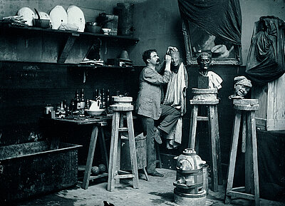 Medardo Rosso working on a bust in his studio.