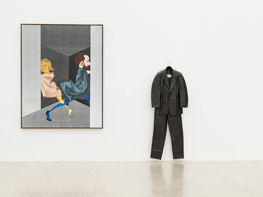  white wall, on the left hangs a painting showing two figures, on the right hangs a black man's suit
