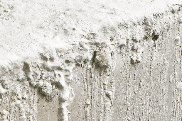 
            
                Nahaufnahme einer strukturierten weißen Wandoberfläche mit dicken Farbschichten, Tropfen und unregelmäßigen Erhebungen. / Close-up of a textured white wall surface with thick paint layers, drips, and irregular protrusions.
            
        