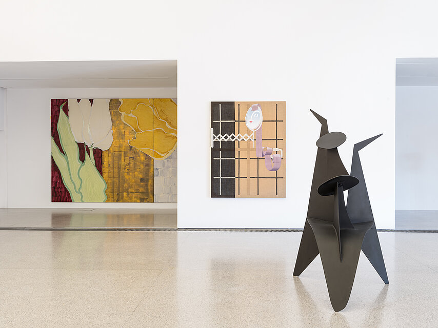 Exhibition view, on the right in the foreground an abstract, dark sculpture, in the centre a brown and black painting, on the left in the background a colourful abstract painting