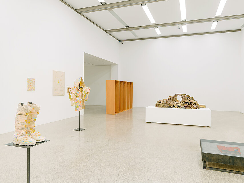  a bright exhibition space with various sculptures in earthy and woody colours