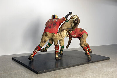 Sculpture of 3 football players showing them in the game.