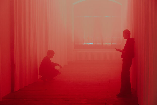 
            
                rot eingefärbtes Bild, zwei Menschen sind im roten Nebel zu sehen
            
        